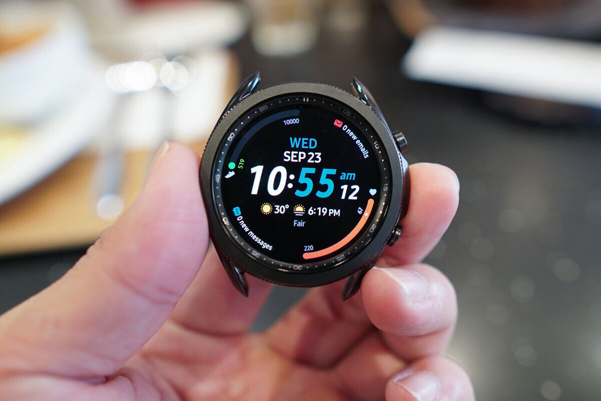 Samsung Galaxy Watch 3 held in a hand with the time and other complications.