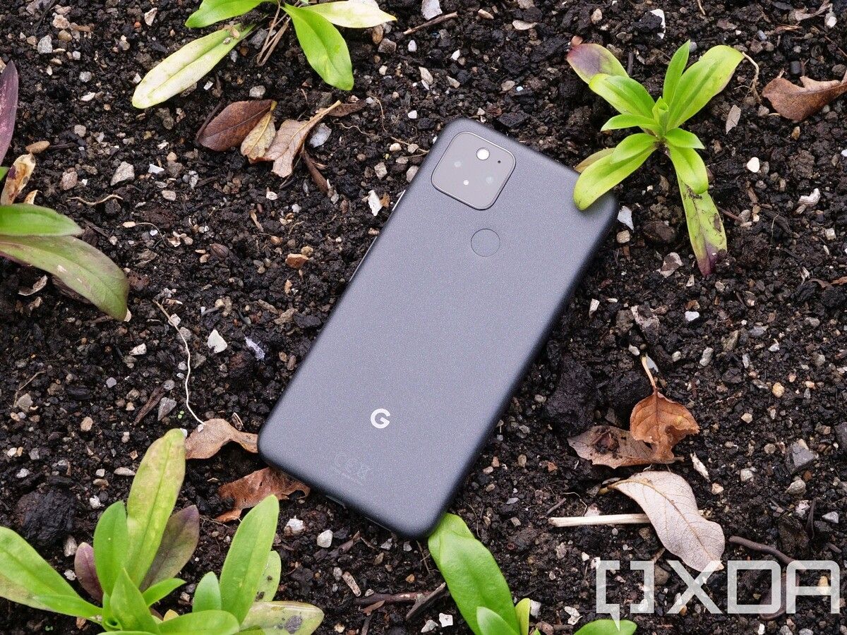 Google Pixel 5 with the back facing up sitting in a soil bed