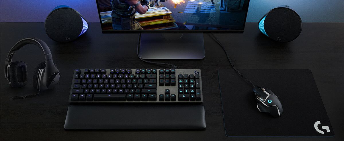 logitech g502 gaming mouse on desk with keyboard and other accessories, backlit