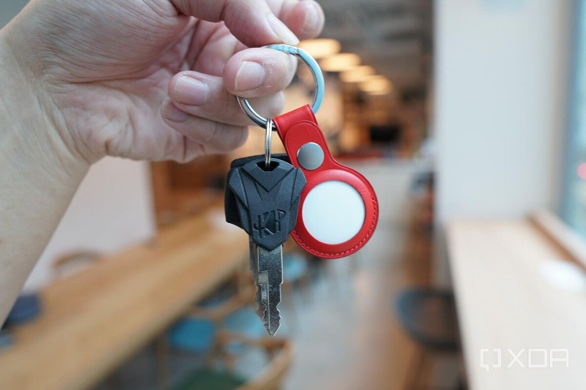 Apple's AirTag in a red leather key ring with some keys.