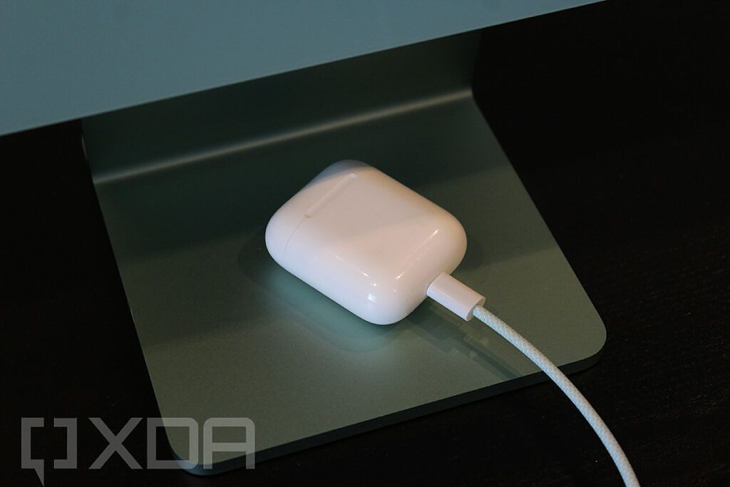 Close-up of AirPods connected to green braided Lightning cable