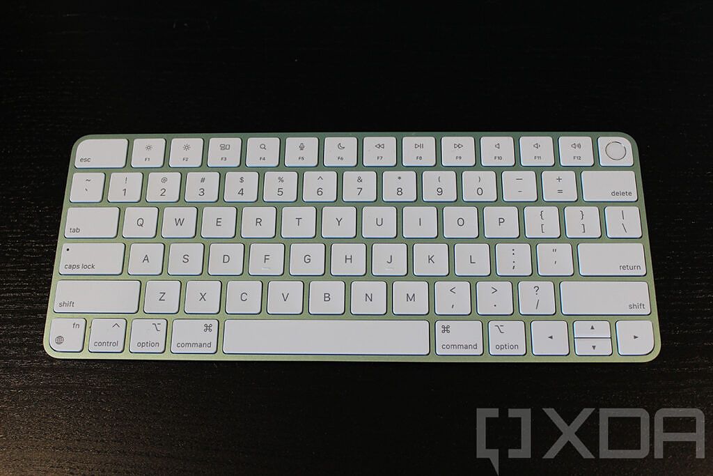 Green Magic Keyboard with Touch ID on black desk