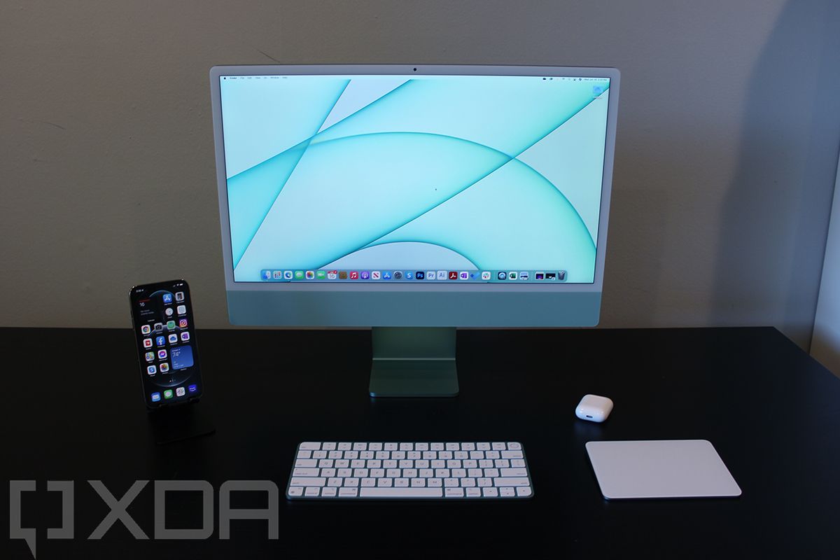Front view of 24-inch iMac with keyboard, mouse, iPhone, and AirPods