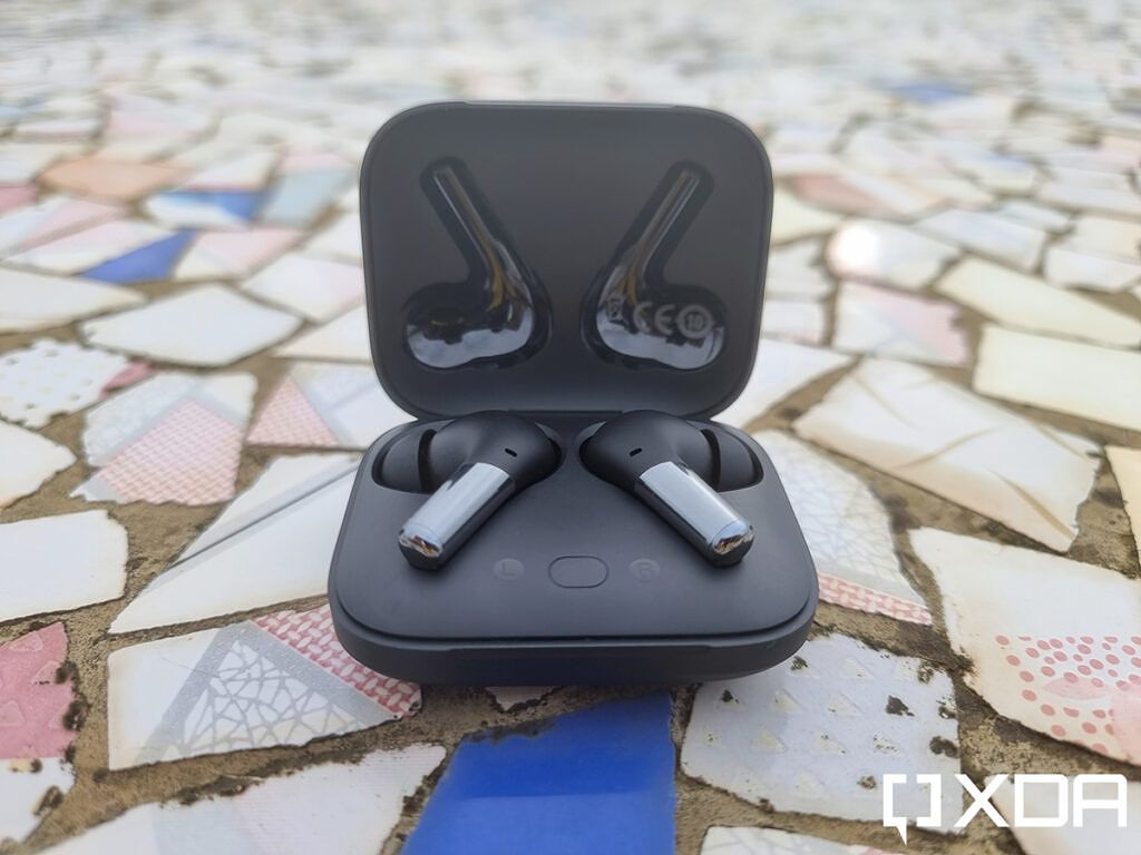OnePlus Buds Pro earbuds kept on a chipped tile floor