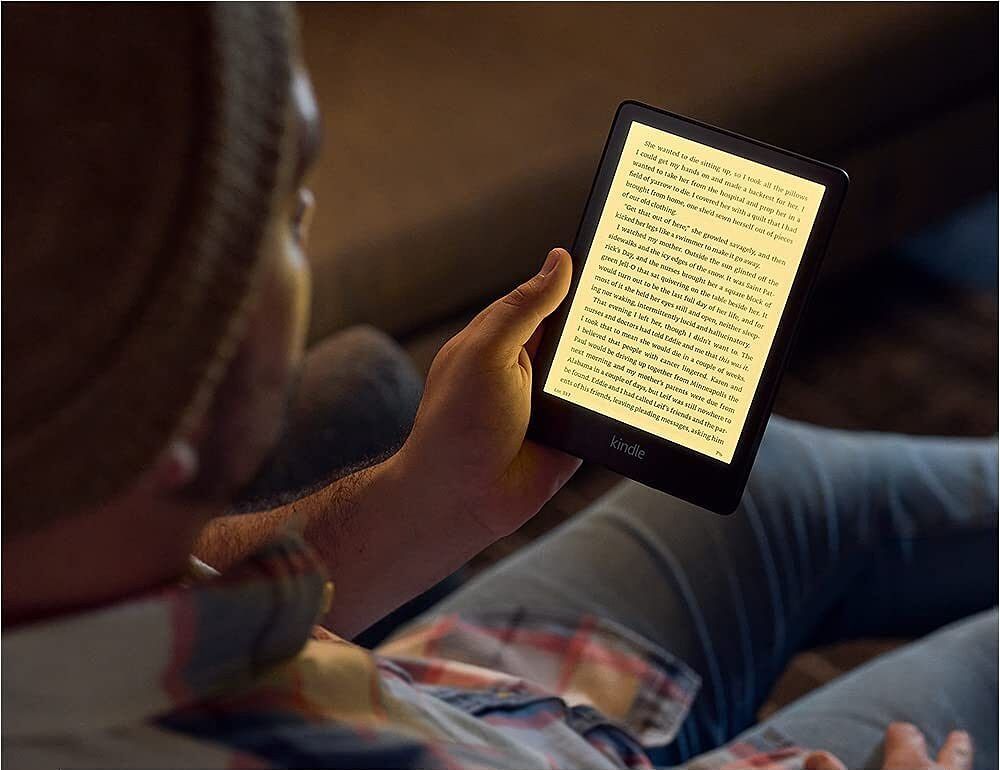 A person looking at the Kindle Paperwhite 11th Gen in a dark room