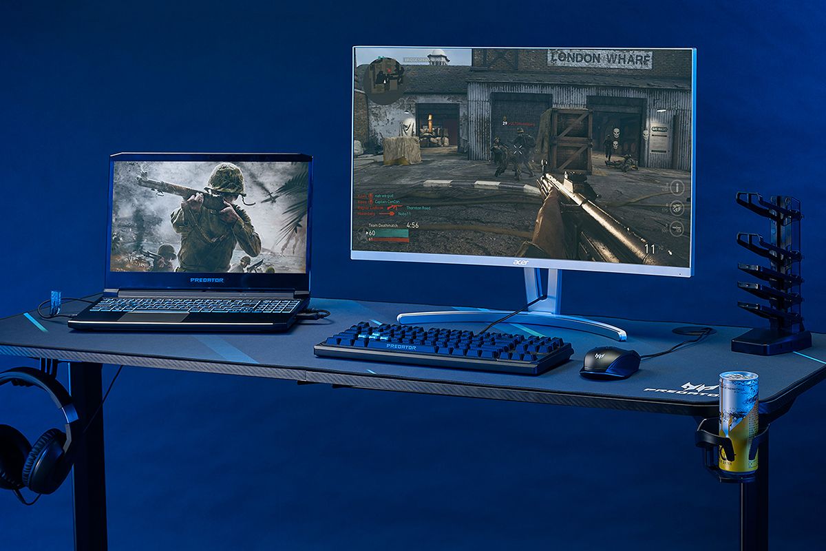Desk with a laptop, keyboard, mouse, energy drink, and headset