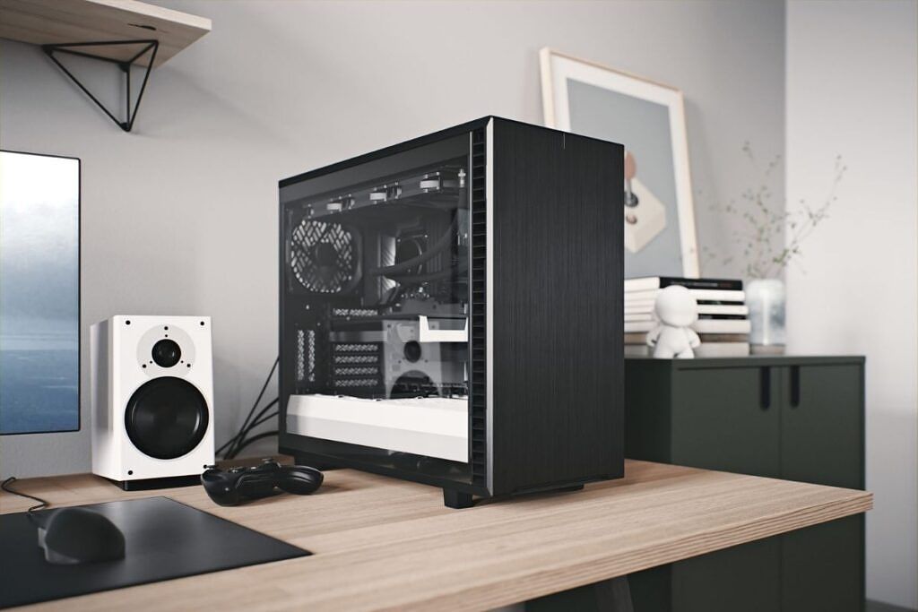 A black PC case with a tempered glass side panel resting on a wooden table