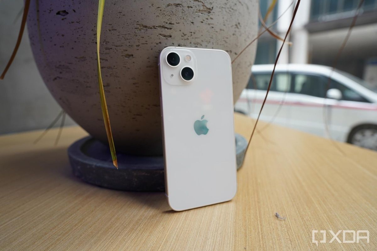 iPhone 13 Pro in white standing in front of a vase