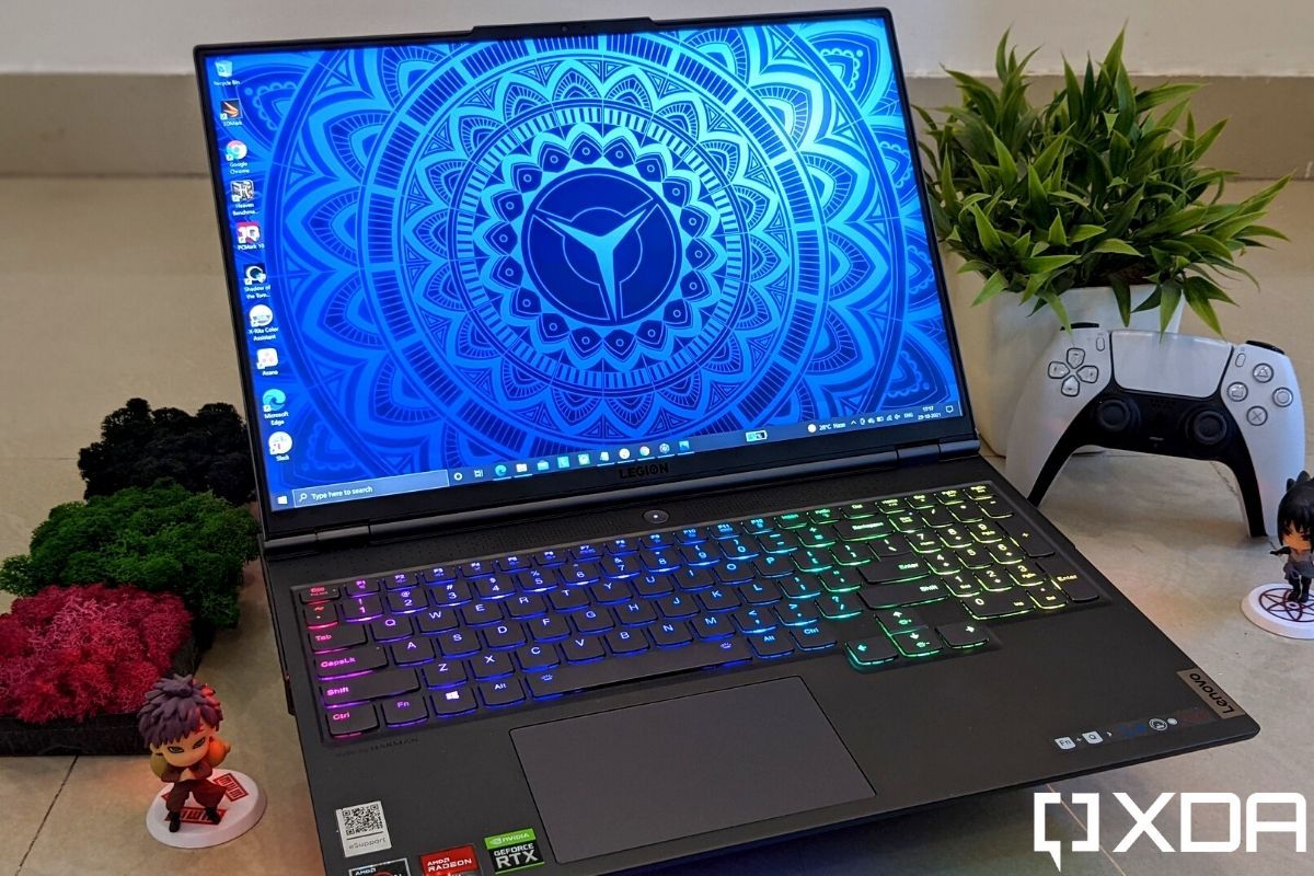 A lenovo laptop with a blue colored wallpaper sitting next to a potted plant