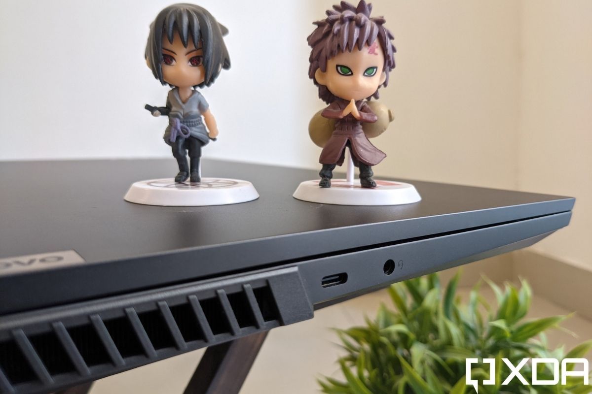 An image showing the left side ports of a grey colored laptop with two action figures on top