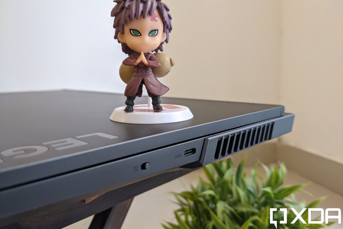 An image showing the ports of a grey colored laptop with an action figure kept on top of it