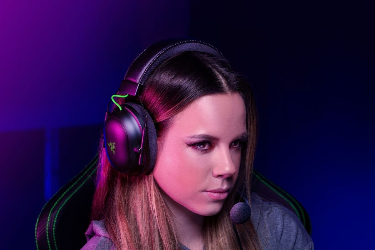 Girl sitting in chair wearing gaming headset against a purple background