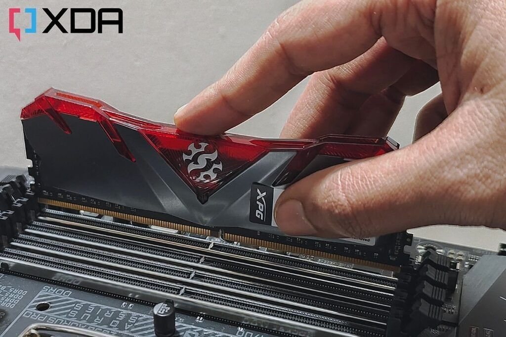 An XPG RAM module with a red-colored heat spreader being installed on a motherboard