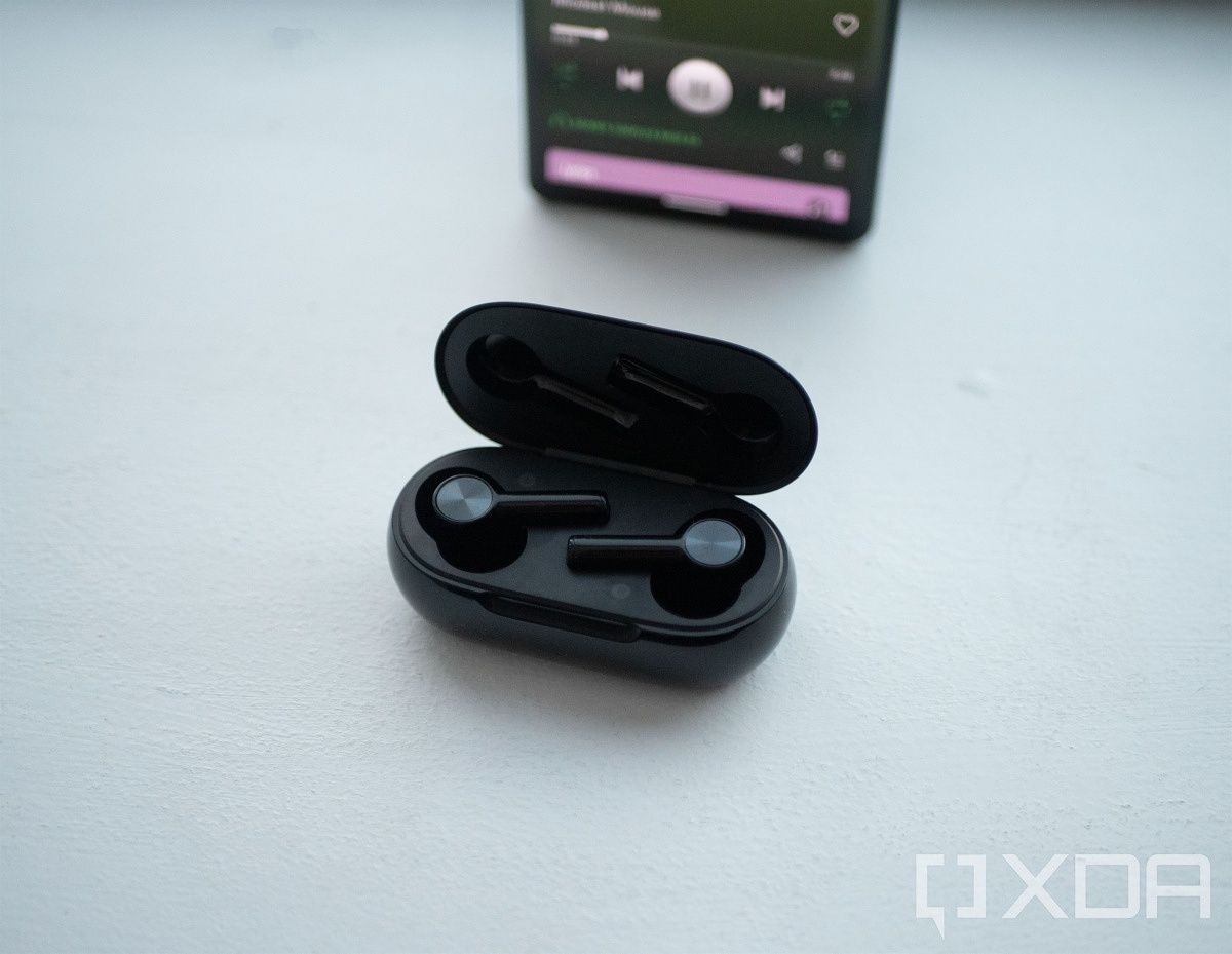 OnePlus Buds Z2 in the case with a phone on Spotify behind them