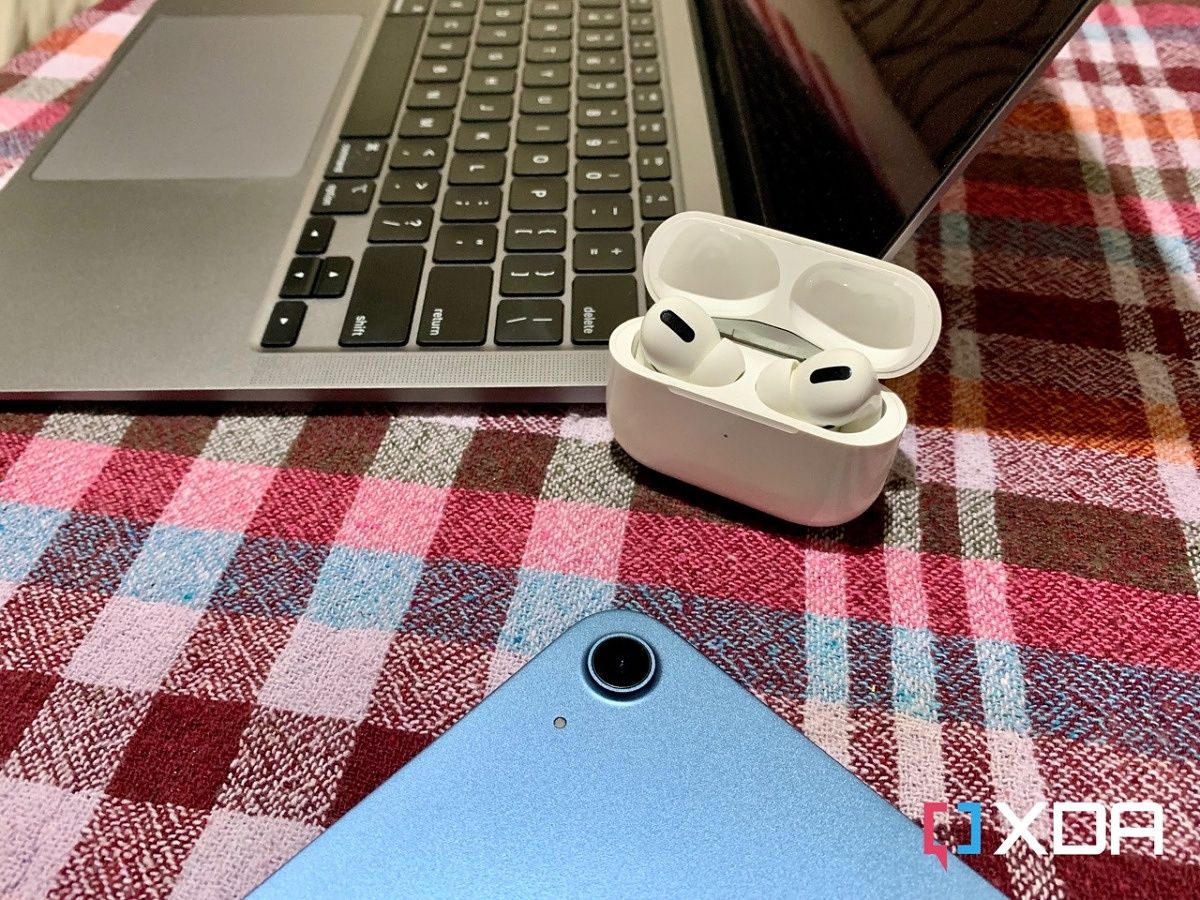 AirPods Pro open case next to MacBook Air M1 and iPad Air 5