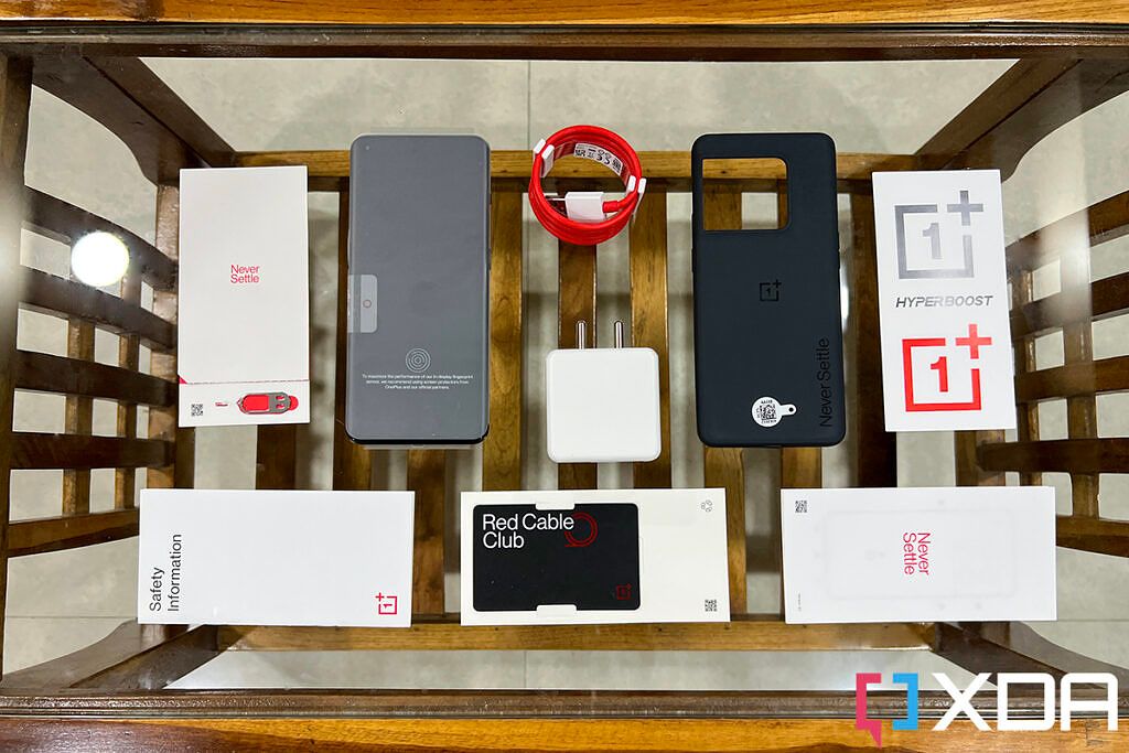 Box contents of the OnePlus 10 Pro laid out on top of a glass table