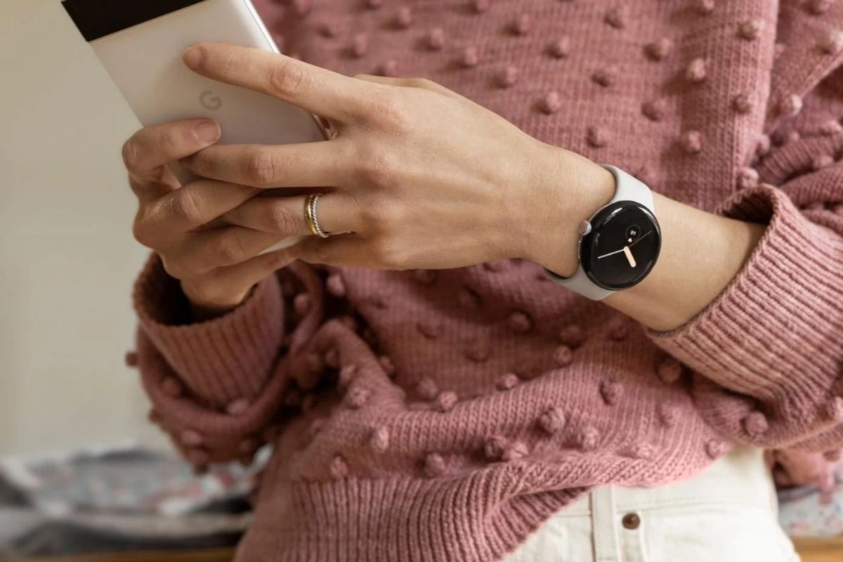 A person wearing the Pixel Watch on the left hand while holding a Pixel with both hands