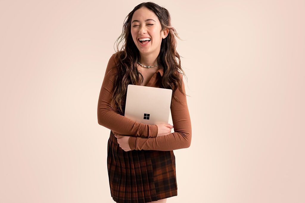 Woman laughing while holding a sandstone Surface Laptop Go 2