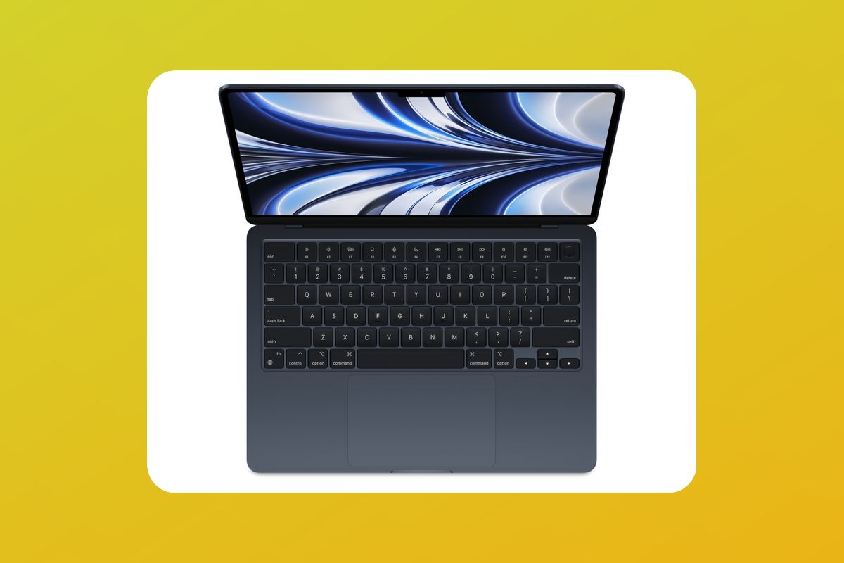 An overhead view of the MacBook Air in a dark blue color, laid over a yellow and orange background