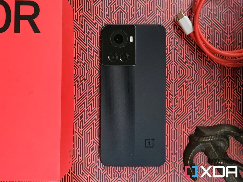 OnePlus 10R next to its retail box on a red-colored background