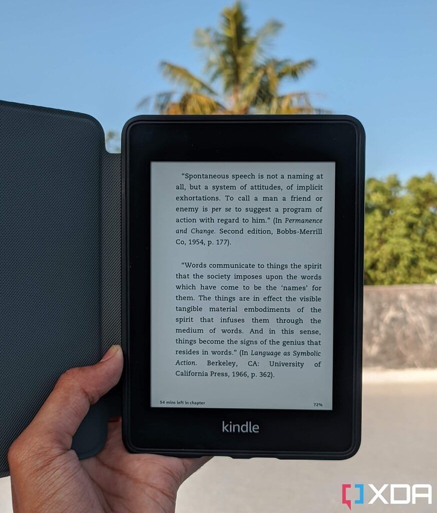 Kindle Paperwhite 10th Gen held in the cover with the folio case open against the blue sky in the background