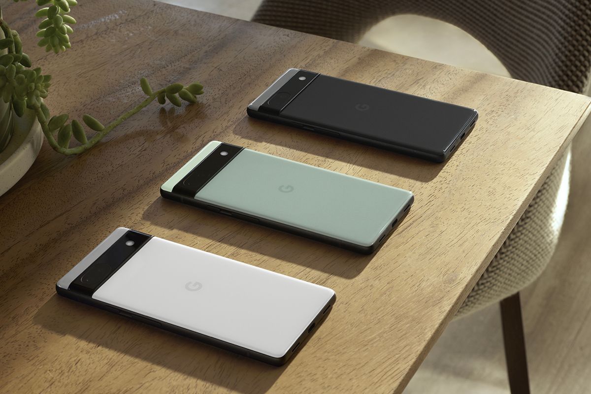 Google Pixel 6a in all three colors on wooden table.