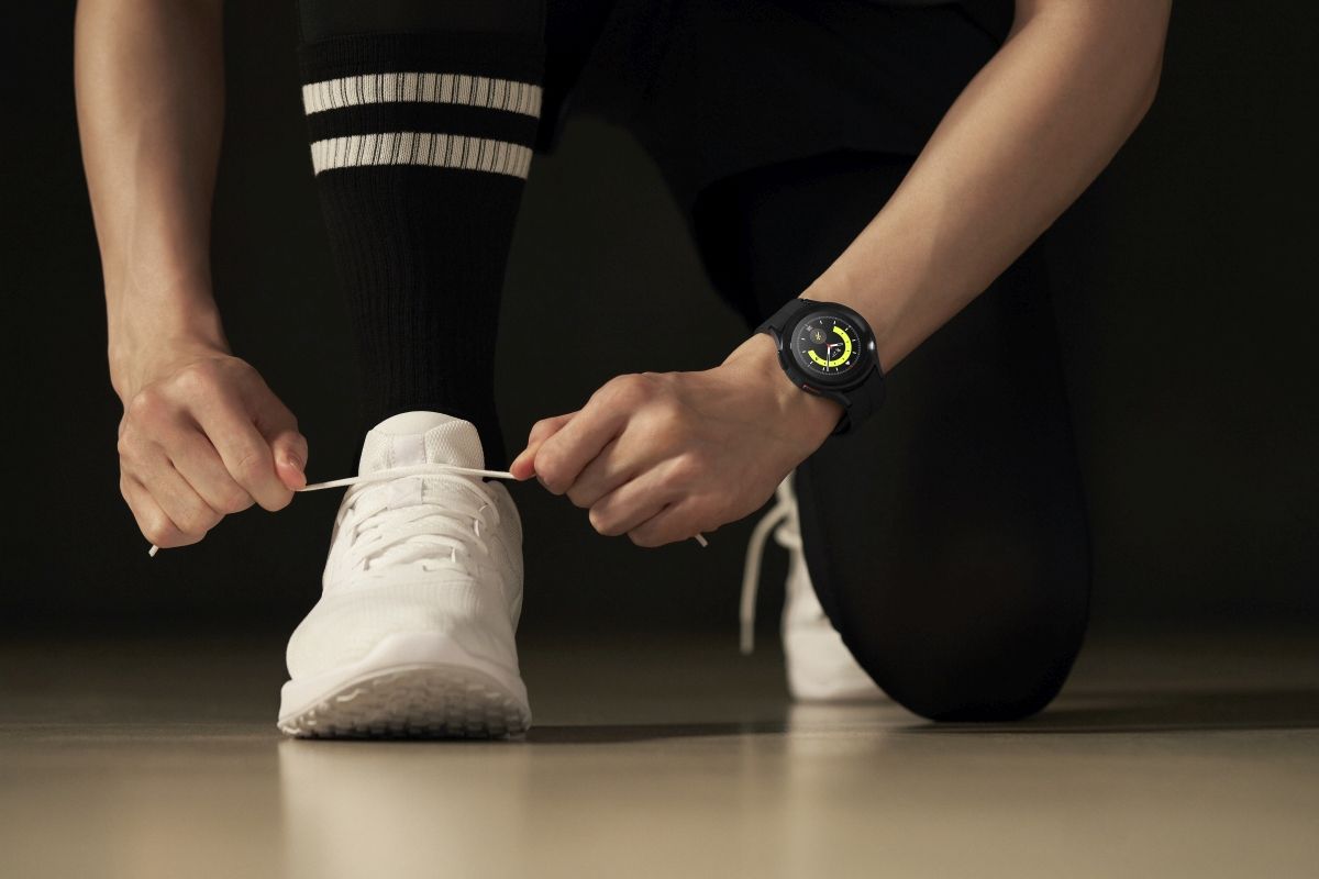 A person wearing the Galaxy Watch 5 on their wrist lacing their shoes.