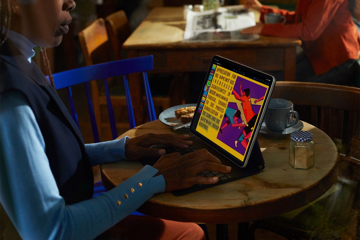 Person using iPad 10 with Apple's new Magic Keyboard accessory at a table in a coffee shop.