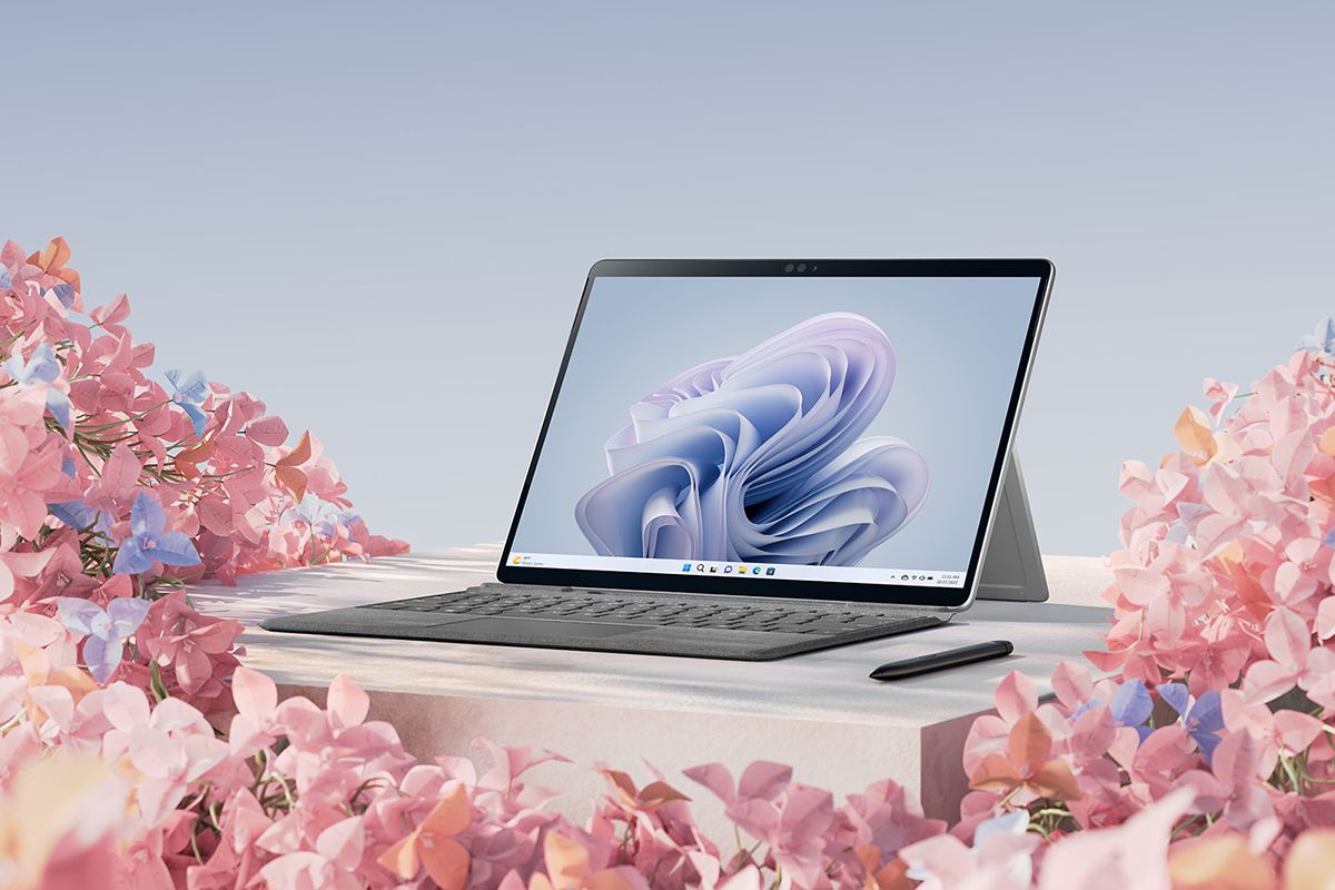 Angled view of the Surface Pro 9 with its Signature Keyboard and Surface Slim Pen 2, surrounded by pink flowers