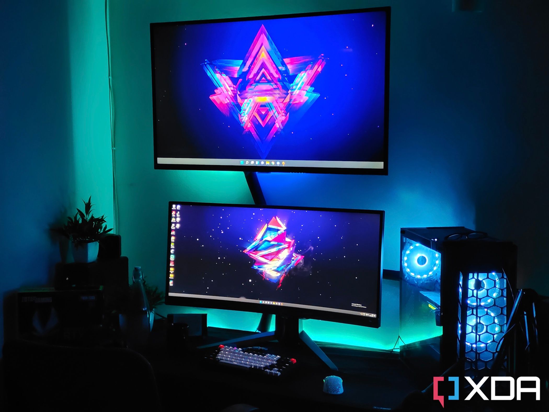 An image showing a gaming setup with a TV, monitor, and a gaming PC case on a desk with some RGB lights.