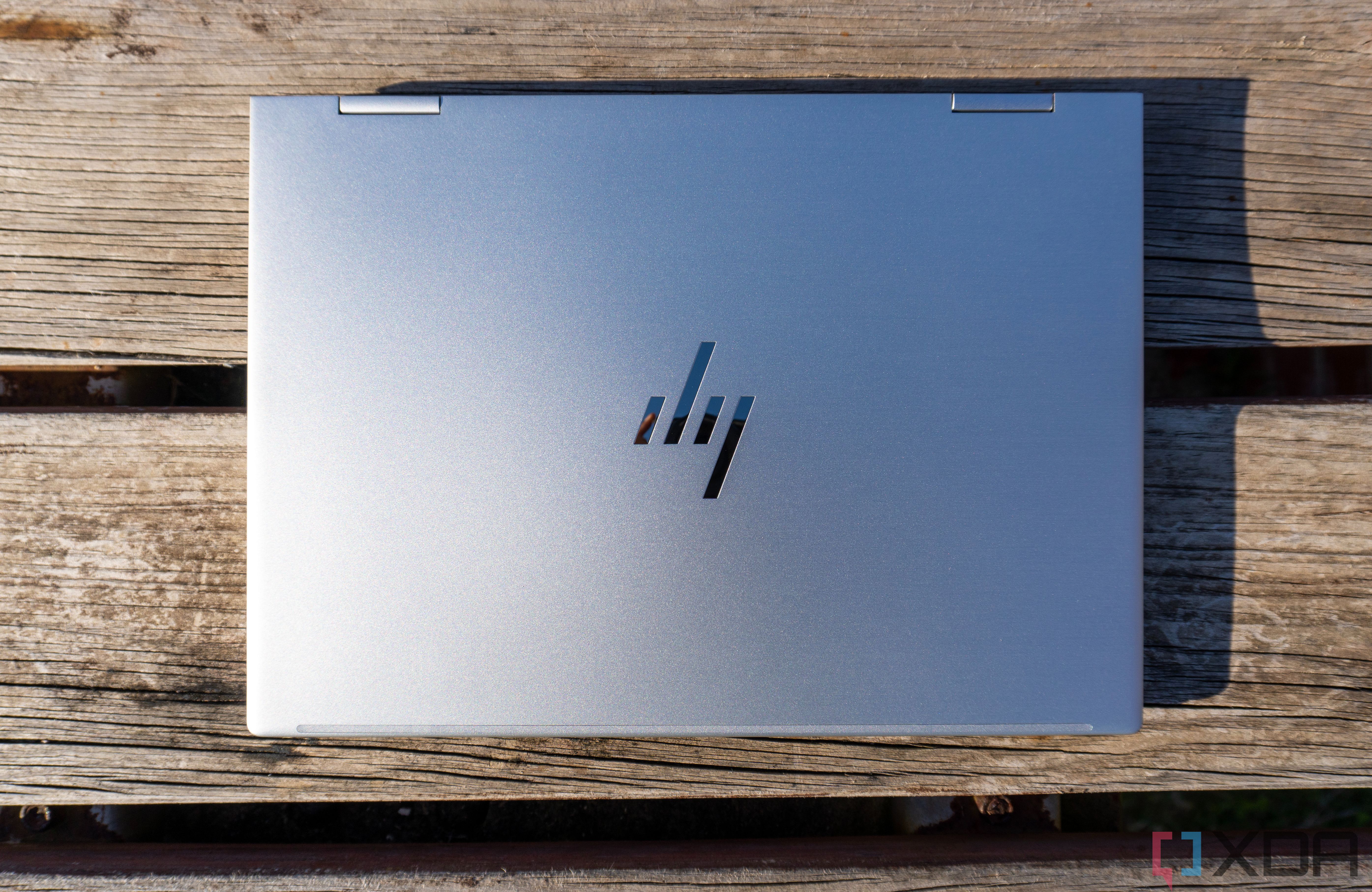 Вид сверху на HP Envy x360 с закрытой крышкой. Ноутбук стоит на деревянном столе.
