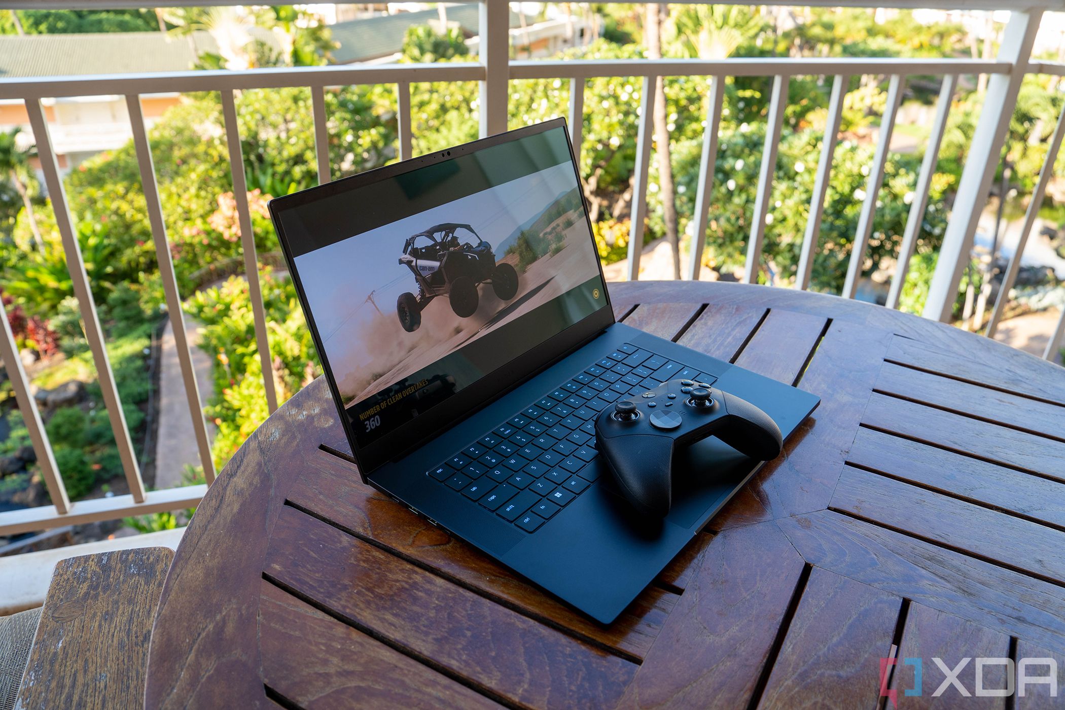 Angled view of black laptop with game controller on wooden table