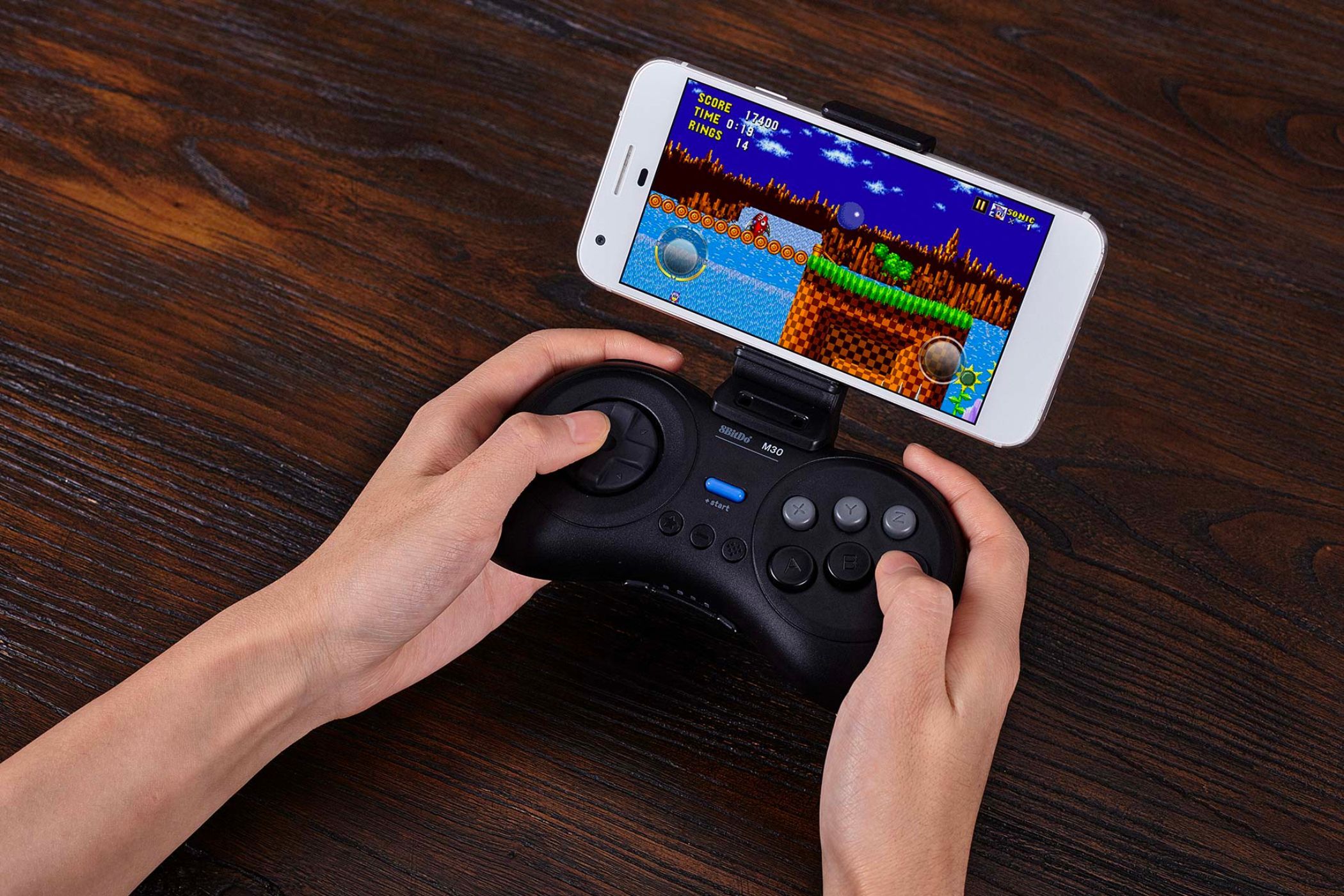 An image showing a person using the 8Bitdo M30 retro controller to play games on a smartophone.