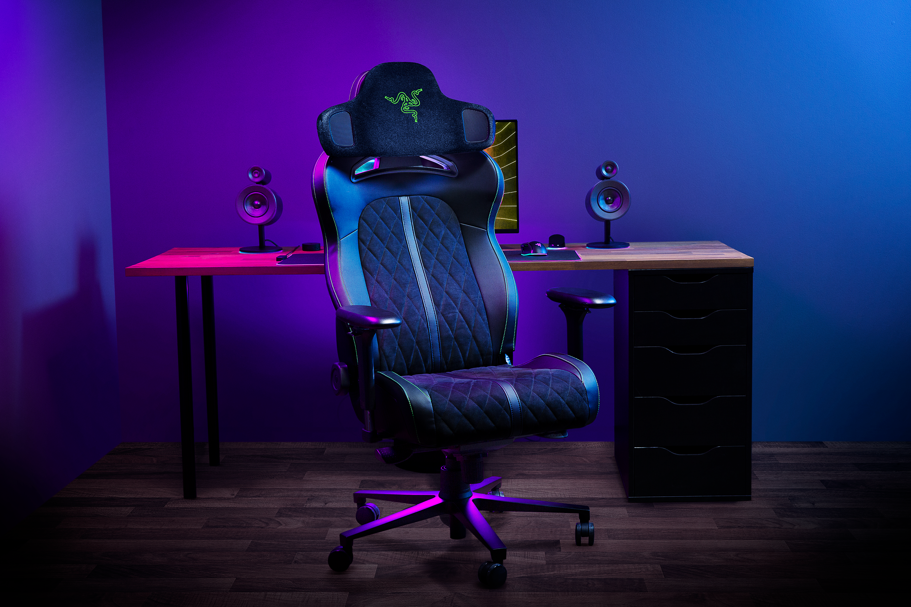 A gaming chair with a Razer-branded headrest mounted on it. The headrest has speakers on both sides.