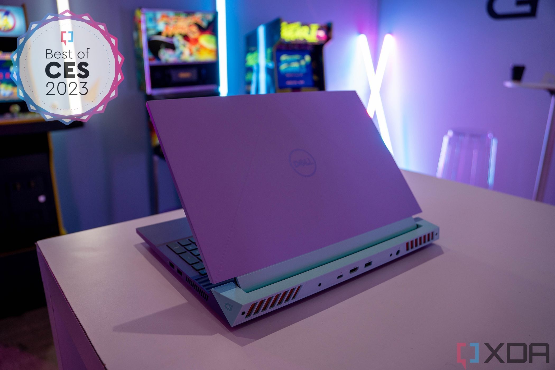 Angled rear view of the Dell G15 laptop facing right, with a purple chassis and mint green accents around the hinge. The top left corner of the image has a badge reading 