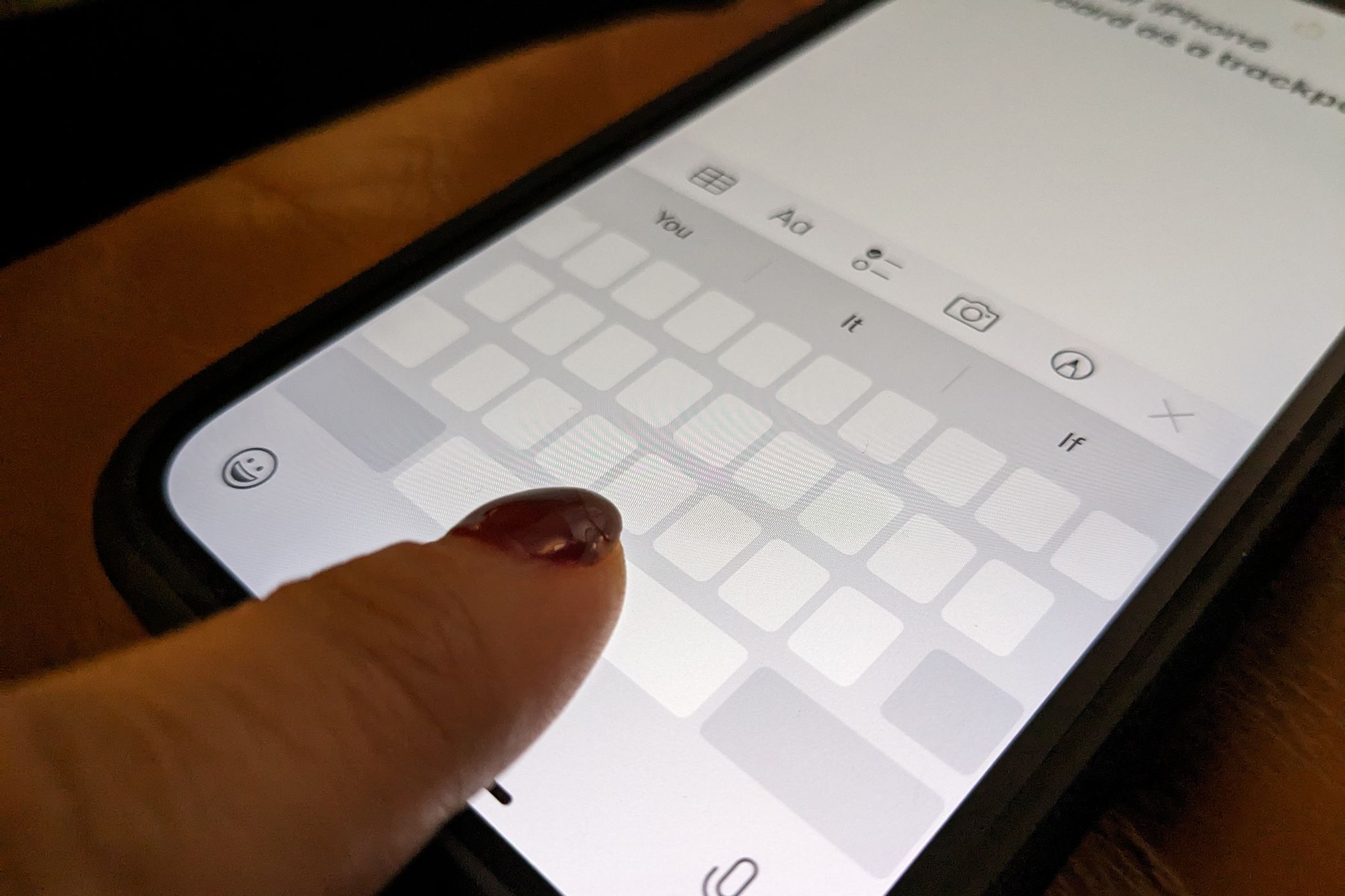 A finger on the spacebar of the iPhone, turning the keyboard into a trackpad.