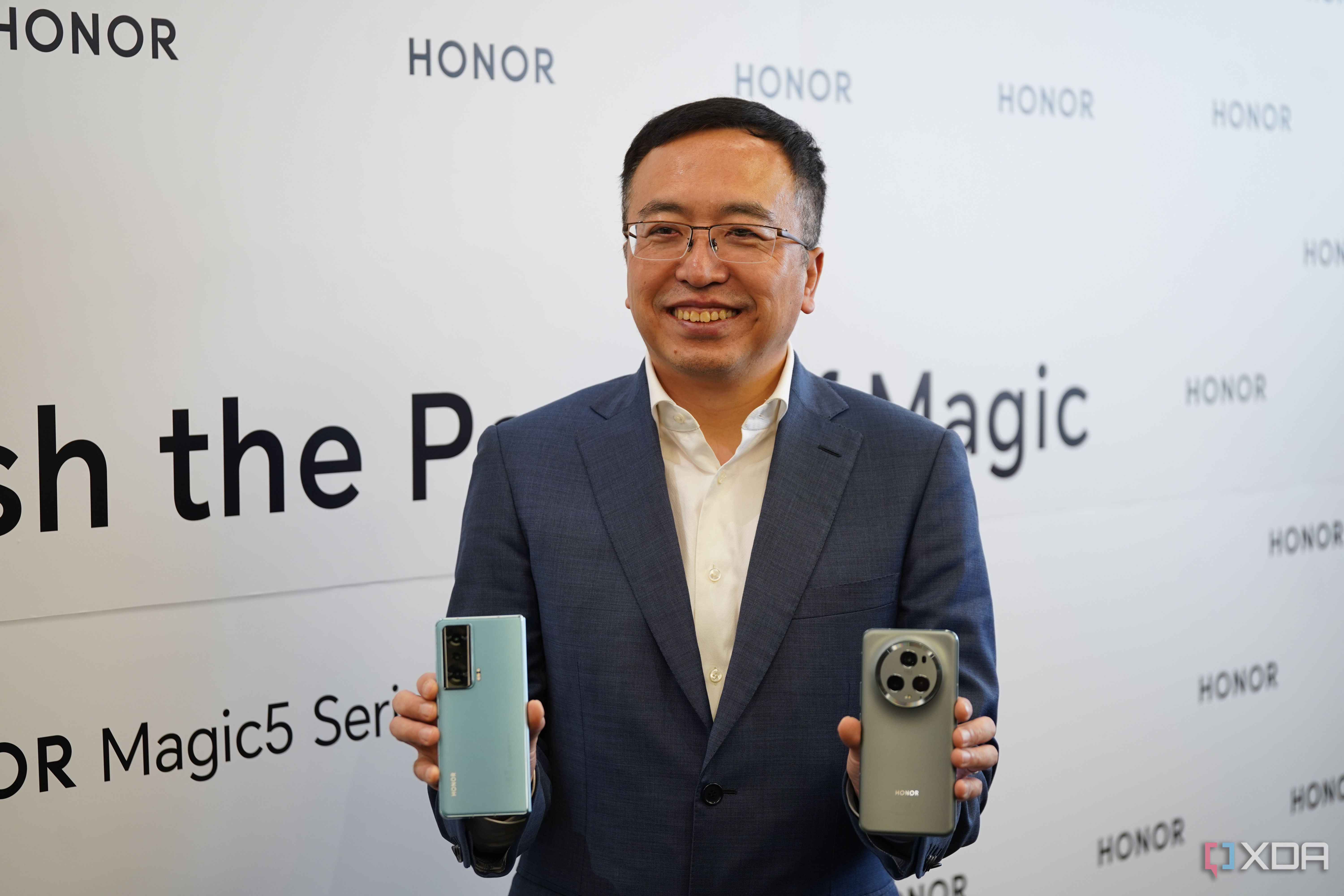 Honor CEO George Zhao standing with Honor flagship phones: Magic 5 Pro and Honor Magic Vs.