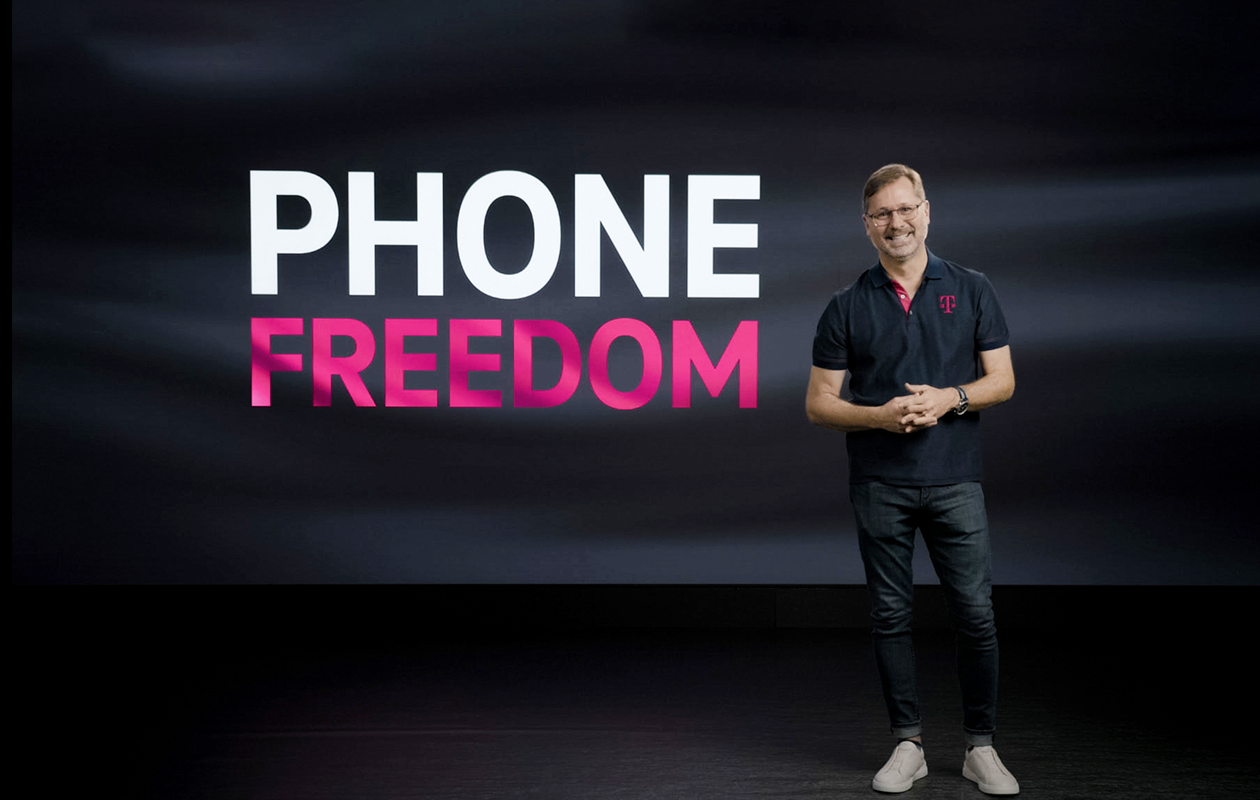 CEO Mike Sievert standing and smiling next T-Mobile Phone Freedom logo