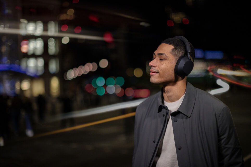 A man wearing Sony WH-1000XM5 headphones outside at night