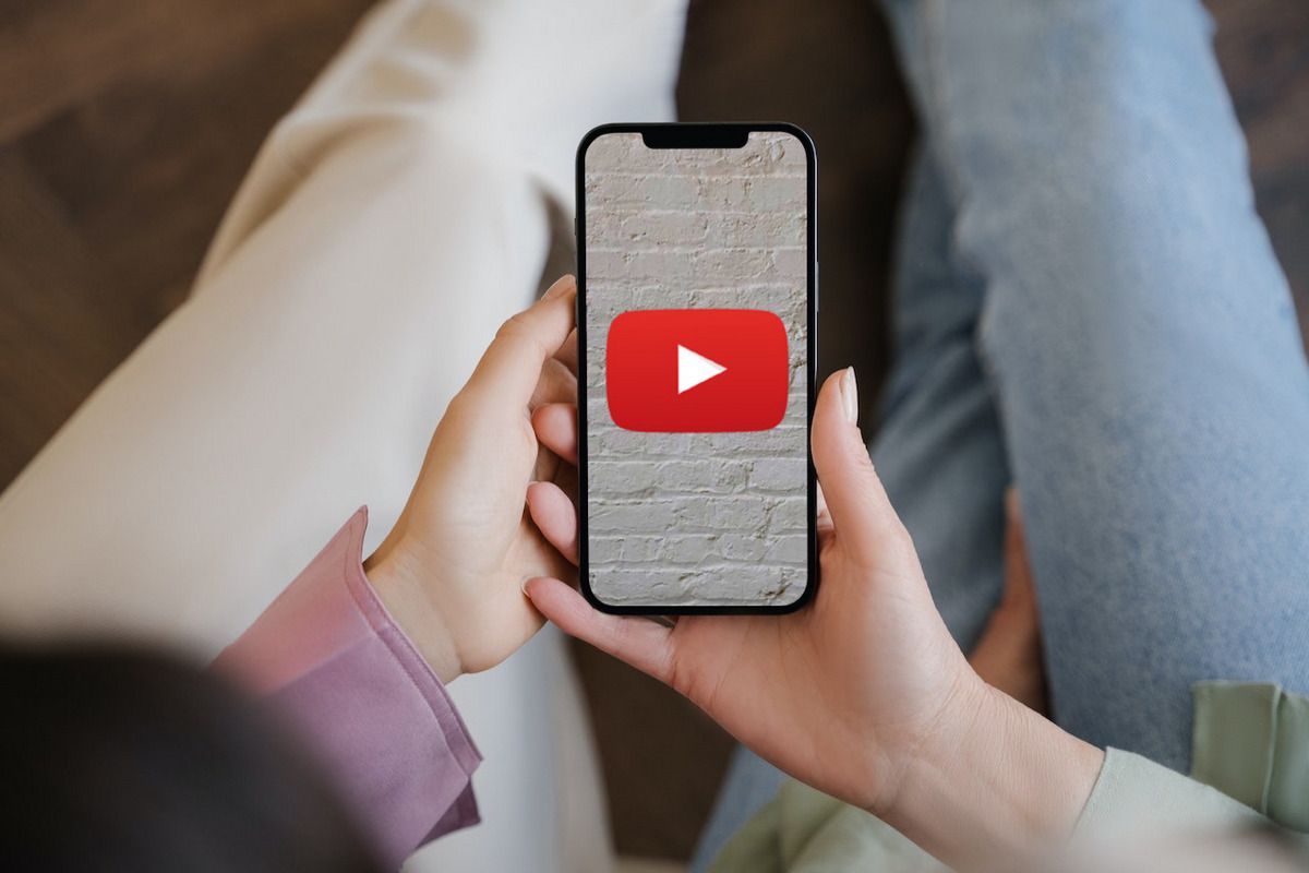 A YouTube logo on an iPhone 12 being held by two people