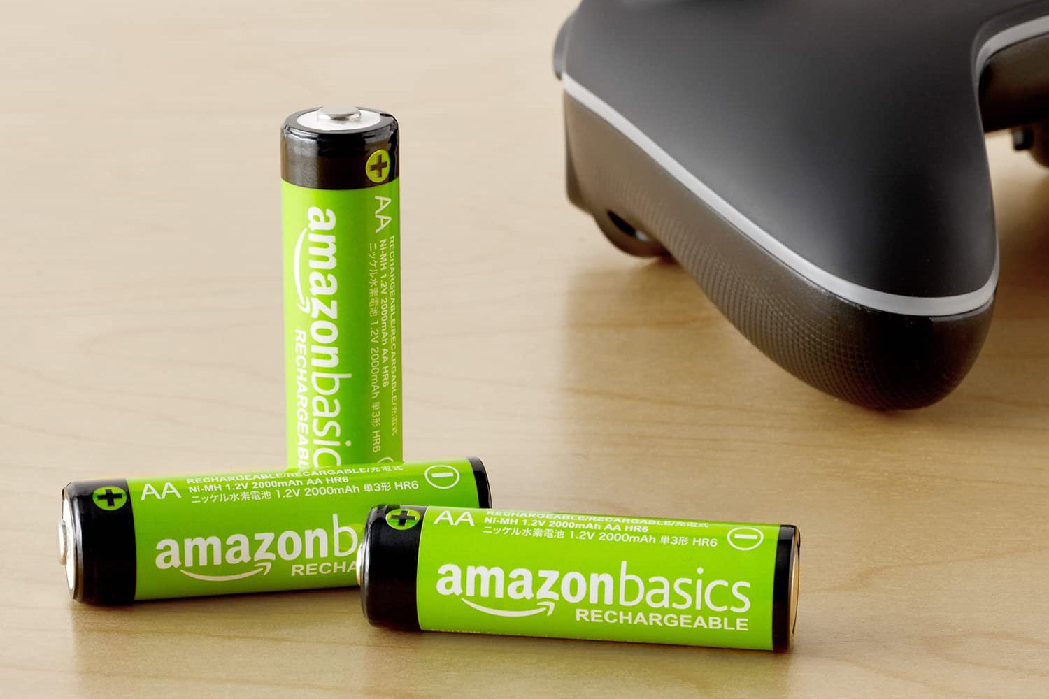 Three Amazon Basics rechargeable AA batteries pictured next to a gaming controller.