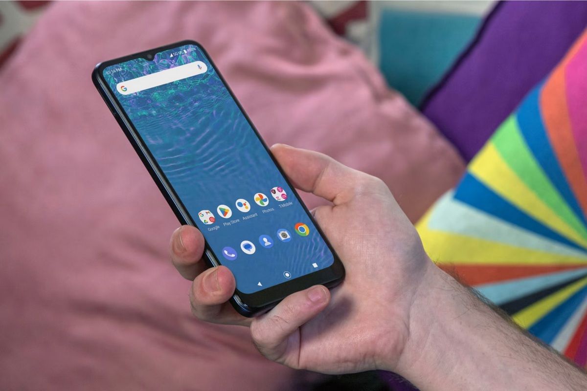 Close-up of an Android smartphone with a teardrop notch and blue wallpaper in a person's hand