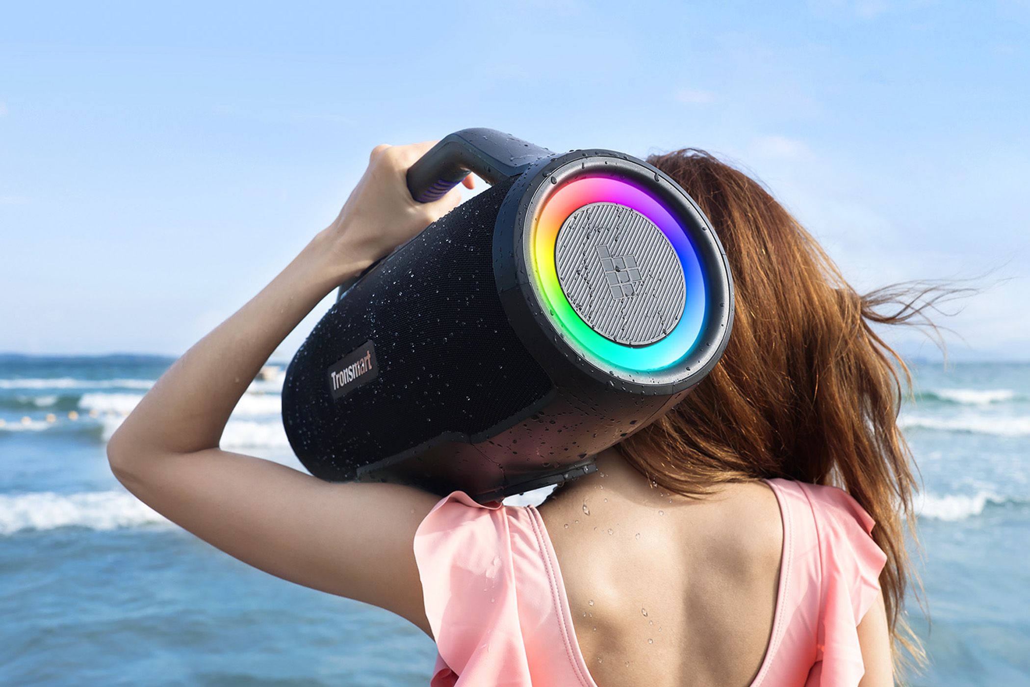 A woman holds the Bang Max speaker on her shoulder