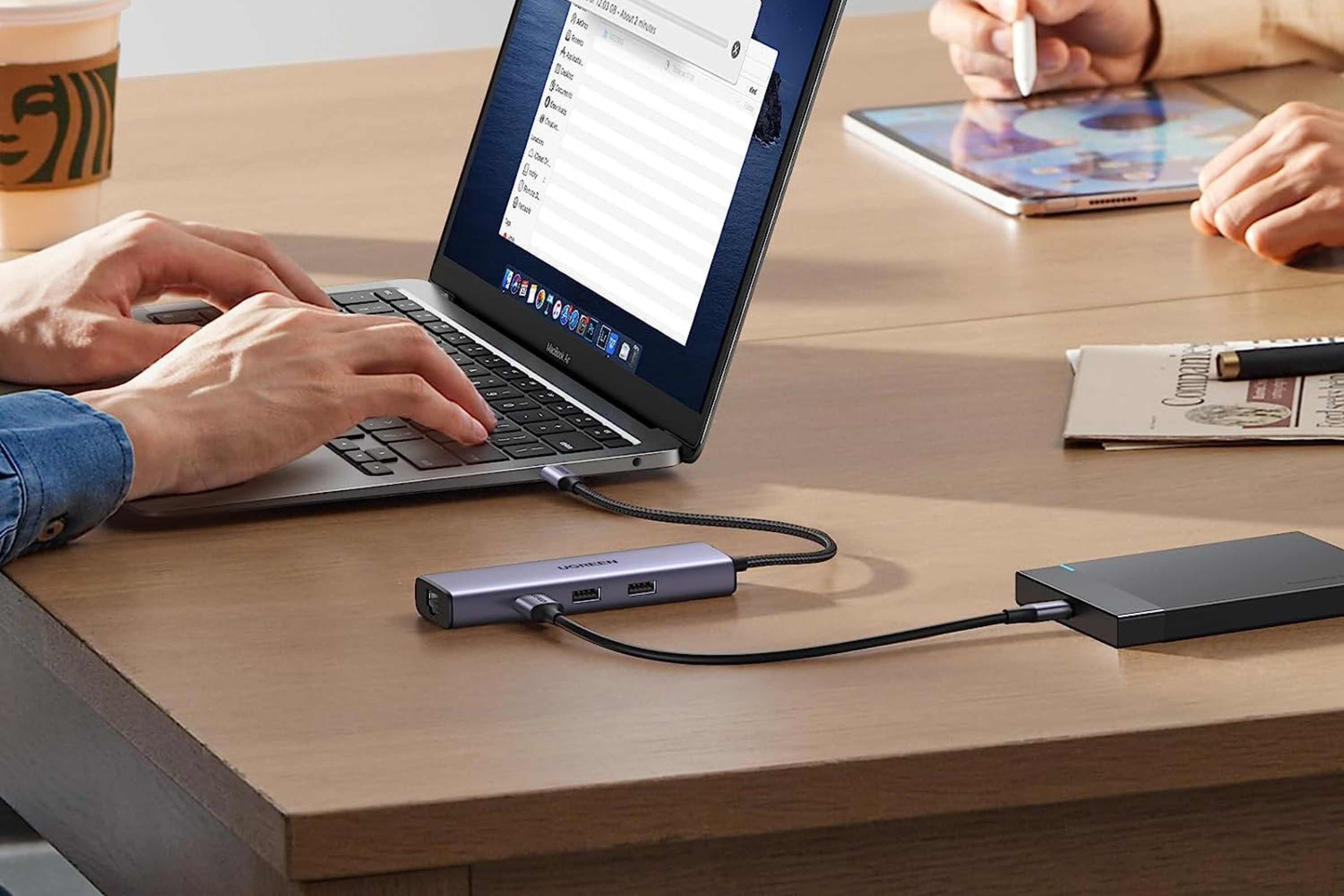 UGREEN Revodok 6-in-1 USB C Hub on table connected to laptop and external drive 