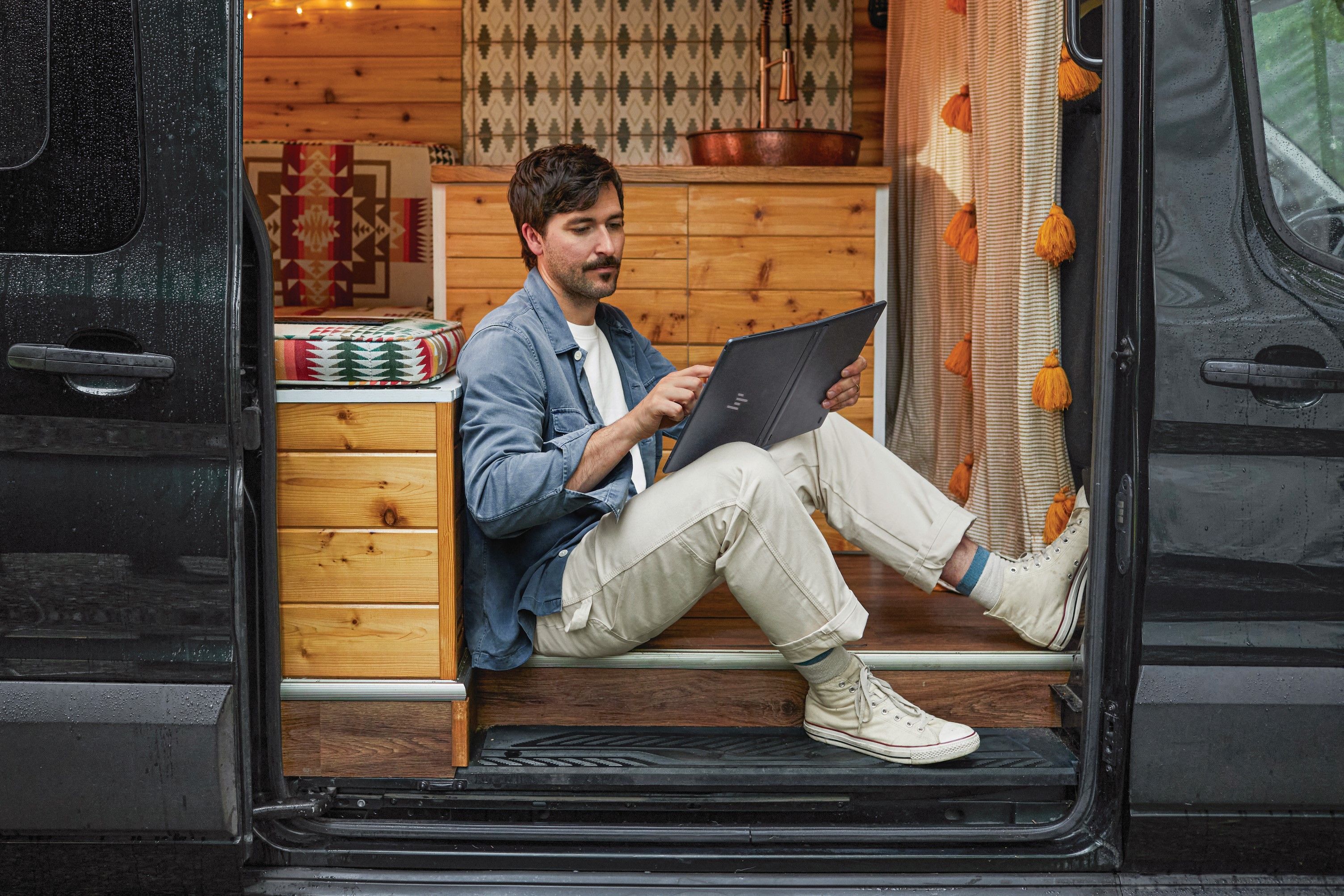 Um homem usando um HP Spectre Fold no modo tablet na traseira de um trailer