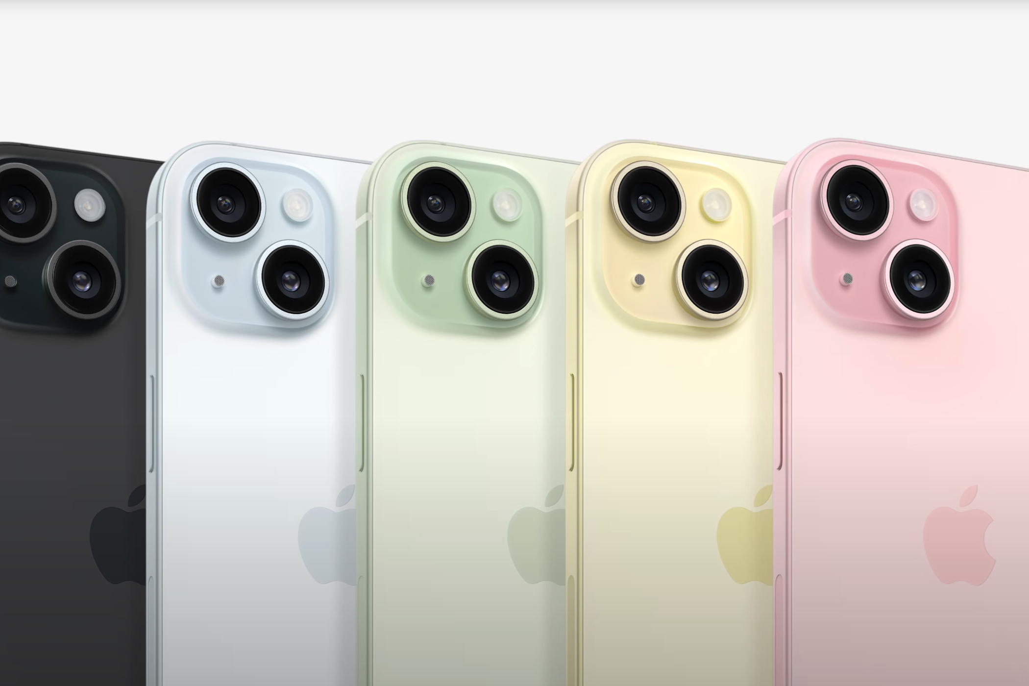iPhone 15 mainline phones in black, blue, green, yellow, and pink all lined up next to each other.