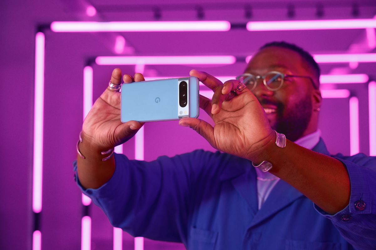 A person holding a Pixel 8 Pro in Bay color horizontally to capture photo/video under neon lights.