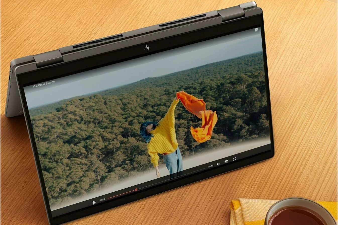 HP Chromebook x360 14c 2 in 1 on a brown desk with a coffe cup in the corner