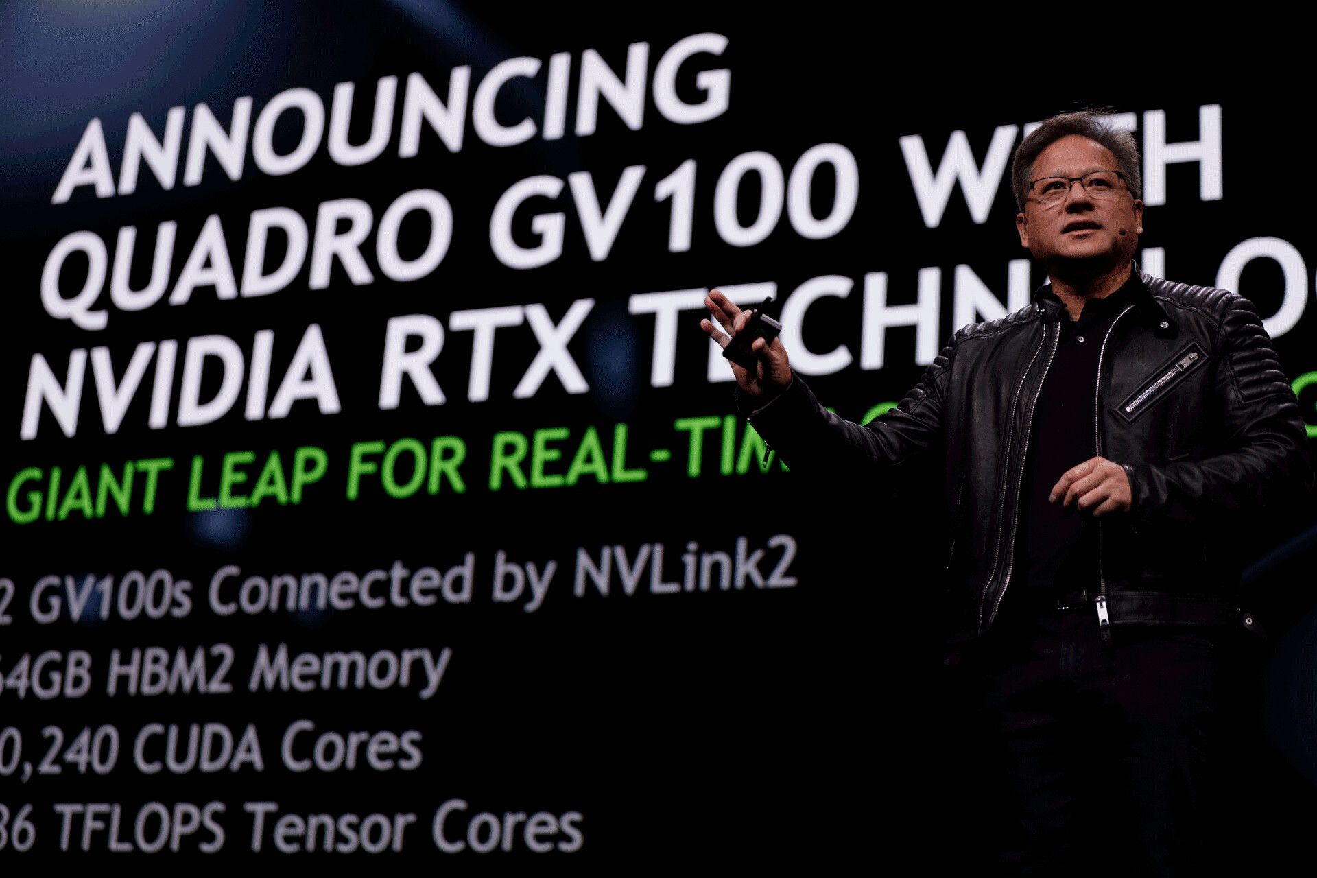 Nvidia CEO Jensen Huang on stage with Quadro GV100 details behind him