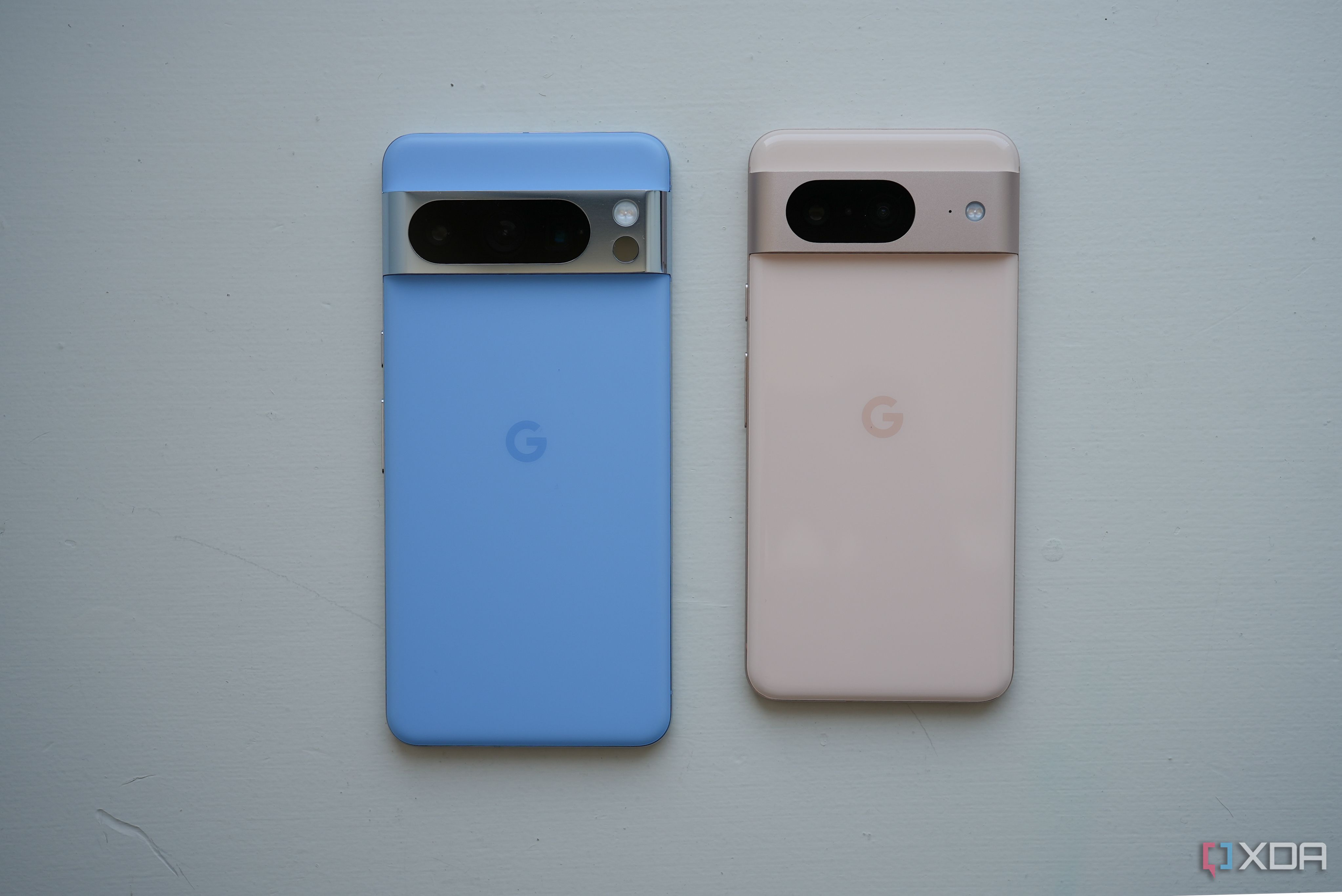 A blue Pixel 8 Pro beside a pink Pixel 8 smartphone. 